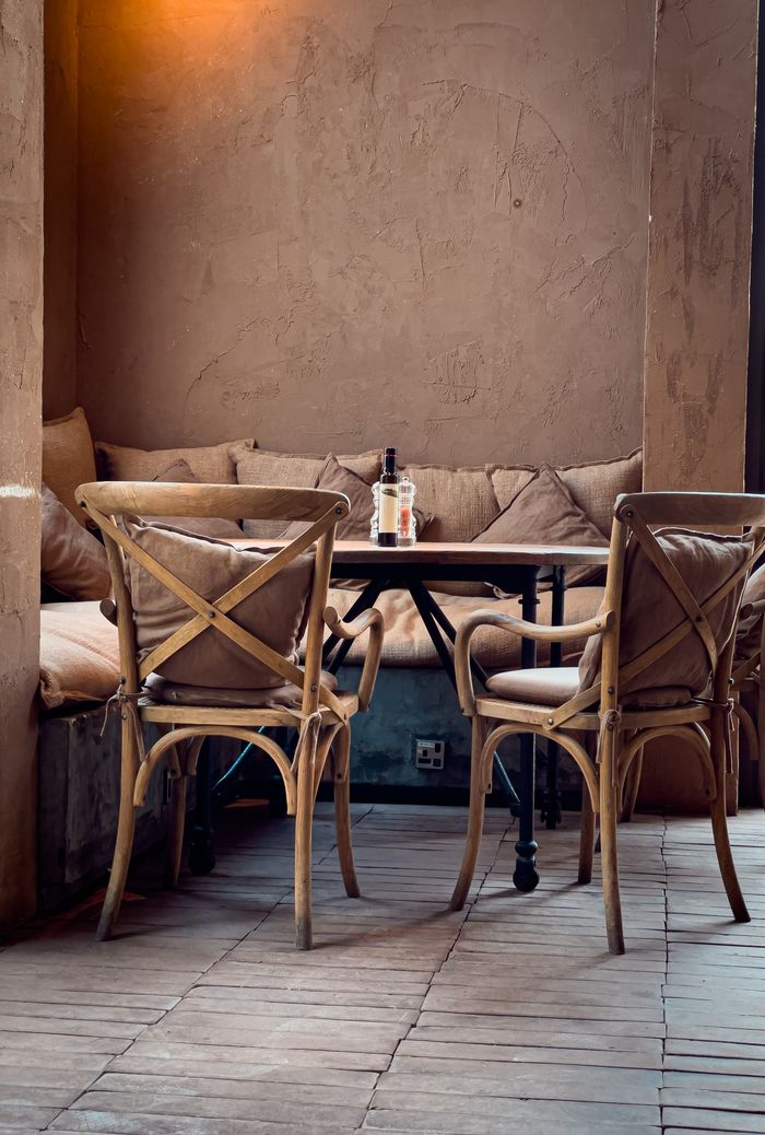 portfolio-05 Warm inviting restaurant corner with wooden chairs and table, perfect for a cozy meal.