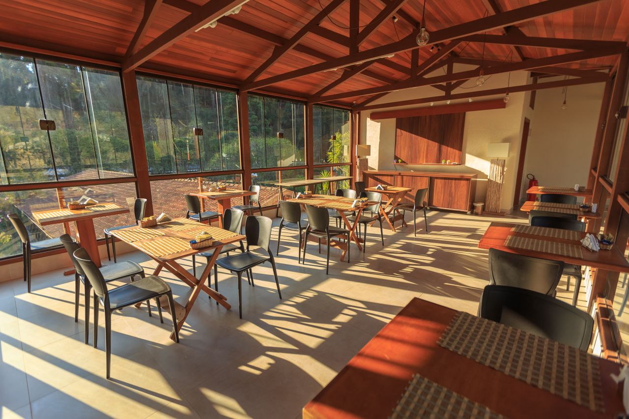 about-img A bright and inviting indoor dining space featuring wooden tables and chairs with natural sunlight streaming in.